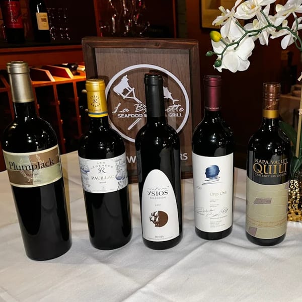 Five bottles of red wine on a white tablecloth with the La Brochette Bistro logo in the background.