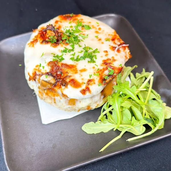 La Brochette Bistro's Croque Monsieur, a cheesy baked sandwich topped with parsley, served with a side salad.