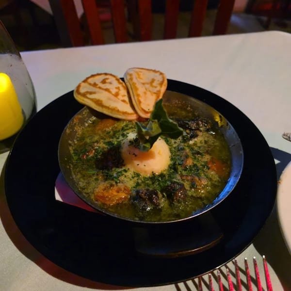La Brochette Bistro's escargots in green sauce, topped with a dollop of butter and two bread slices.