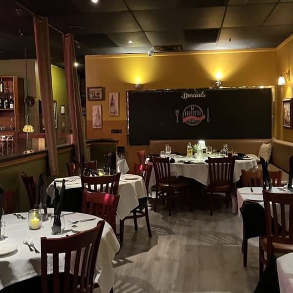 La Brochette Bistro's dining room with white-clothed tables, dark wooden chairs, and warm lighting.