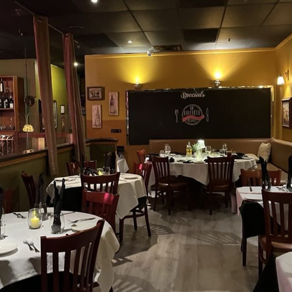La Brochette Bistro's dining room with white-clothed tables, dark wooden chairs, and warm lighting.