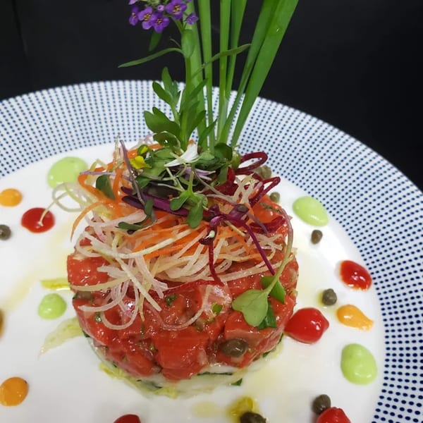 La Brochette Bistro's tuna tartare, topped with shredded vegetables and microgreens, on a white plate.