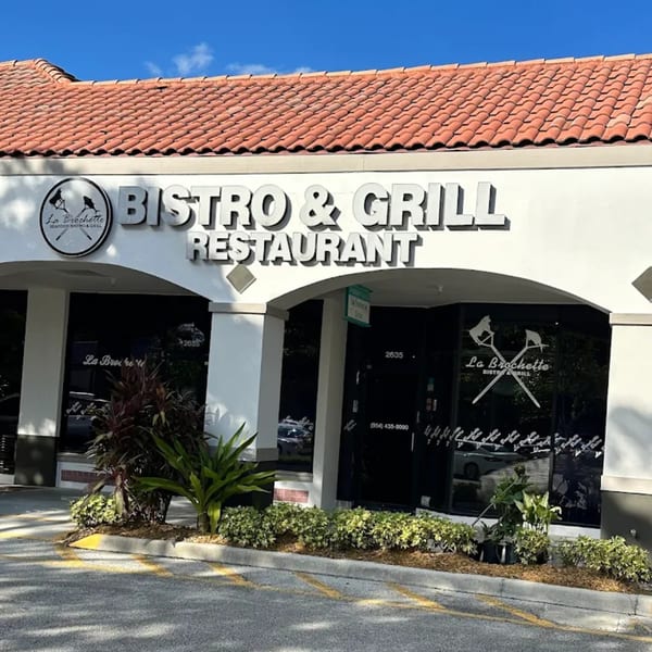 Exterior of La Brochette Bistro & Grill, featuring a white facade, red tile roof, and dark windows.