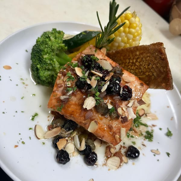 Salmon with blueberries, almonds, and capers, served with broccoli, corn, and zucchini.