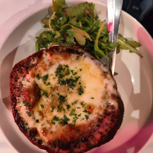 French onion soup with melted cheese and fresh parsley, served with a side salad.